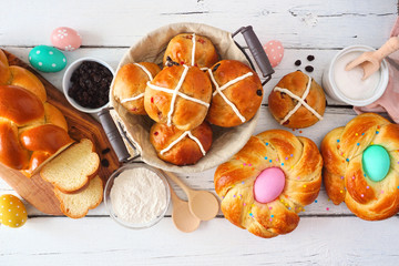 Easter table scene with a selection of fresh breads. Above view over a white wood background. Spring holiday baking concept.