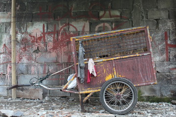 Fototapeta na wymiar Old garbage cart with background Gray wall pattern made of concrete bricks. looks brick is dirty and full of scribbles