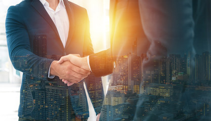 Handshake of 2 businessman in a black suit double exposure the business center city