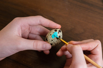 easter, holidays, tradition and people concept - close up of woman hands coloring easter Quail eggs with colors and brush
