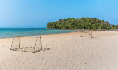 Small football field on white sand beach with blue sky and ocean on sunny day.