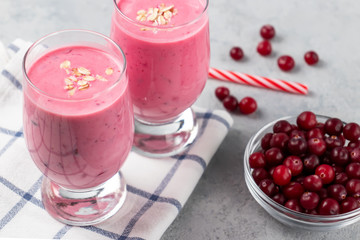 Two glasses with freshly homemade smoothie of yogurt, oatmeal and cranberries on a gray table. Healthy eating concept