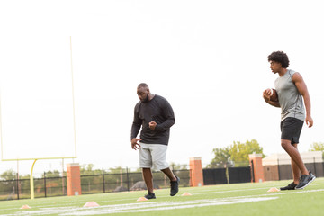 American Football coach training a young athlete.