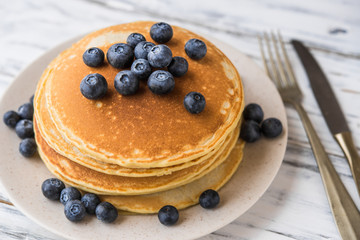 Close up of fluffy pancakes with blueberries against white wooden background