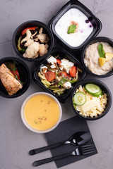 Tasty lunch in plastic containers on grey table close up, top view