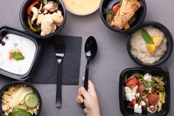 Vegan meal, rice, salad, avocado, cabbage, cream soup on grey background, flat lay. Delicious balanced food concept, kid holding black spoon and fork