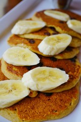 Platter of chocolate chip vegan pancakes with fresh banana slices