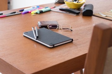 notebook, pen, wallet and glasses on wooden table.