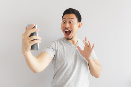 Wow face of man in grey t-shirt get surprised on the smartphone.