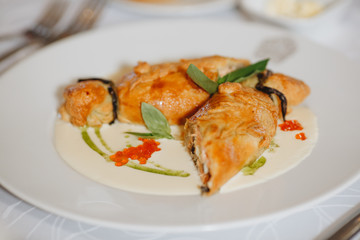 Pie with sauerkraut and fish, Russian kulebyaka. On a white plate and a wooden table, behind a brown tablecloth, side view at an angle, close
