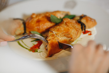 Pie with sauerkraut and fish, Russian kulebyaka. On a white plate and a wooden table, behind a brown tablecloth, side view at an angle, close