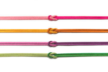 leather string neatly placed in rows. four color threads isolated on white background. red, ornage, yellow, pink, green, purple attached by a knot. seamless pattern with repeated. 