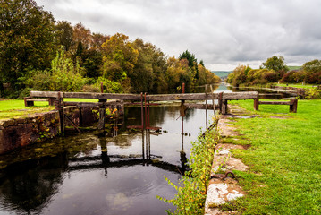 Looking towards the town of Ulverston at Canal Foot, Cumbria. The broken lock gates are reflected in the canal on an Autumn day.