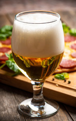 Freshly brewed beer and pepperoni pizza in bar. Selective focus. Shallow depth of field.