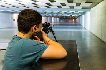 Teen learning marksmanship of shooting gun and rifle safely at firearms education center / range
