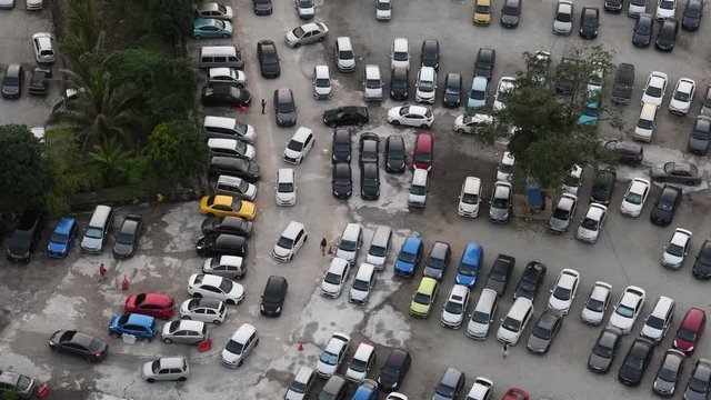 Time lapse top view of cars leaving car park after work in Johor Bahru, Malaysia. Birds eye view of cars. Aerial view of parking lot filled with cars. 4K video