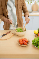 Young man preparing healthy vegetable salad
