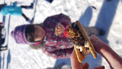 Hand holding freshly made s'more, cute little child on the background