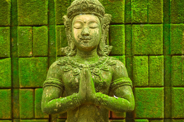 Stucco figure, carved stone Buddha head statue The face of a holy angel in Buddhism Was placed outdoors in the midst of moisture and green moss
