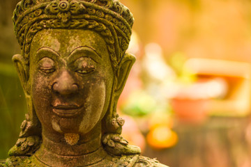 Stucco figure, carved stone Buddha head statue The face of a holy angel in Buddhism Was placed outdoors in the midst of moisture and green moss