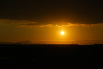 Orange sunset with clouds on the sky over the fields