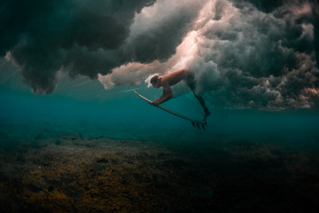 Surfer dives under the powerful wave to safely pass it