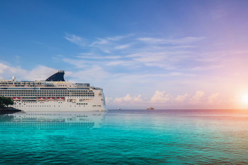 Cruise ship, large luxury white cruise ship liner on blue sea water and cloudy sky background.