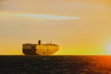 Fototapeta premium Auto car carrier ship, ship in the sea, logistics and transportation of international, ship in ocean at twilight with sky sun set, freight Transportation, shipping