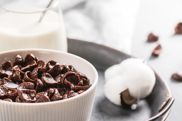 Milk with chocolate corn flakes cereal in bowl