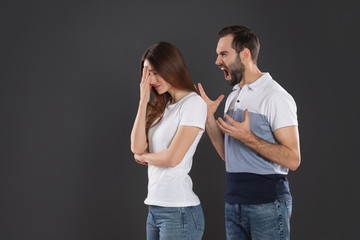 Man shouting at his girlfriend on black background. Relationship problems