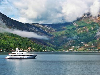 calm sea, green mountains with clouds, white yacht sailing on the sea, sunny day, Montenegro