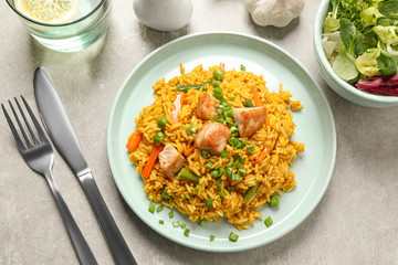 Delicious rice pilaf with vegetables and chicken served on light grey table, flat lay