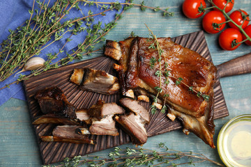 Delicious roasted ribs served on light blue wooden table, flat lay