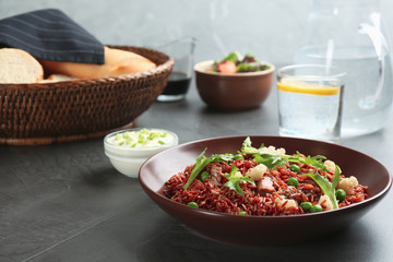 Tasty brown rice with meat and vegetables served on dark grey table