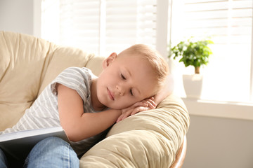 Cute little boy sleeping in papasan chair at home