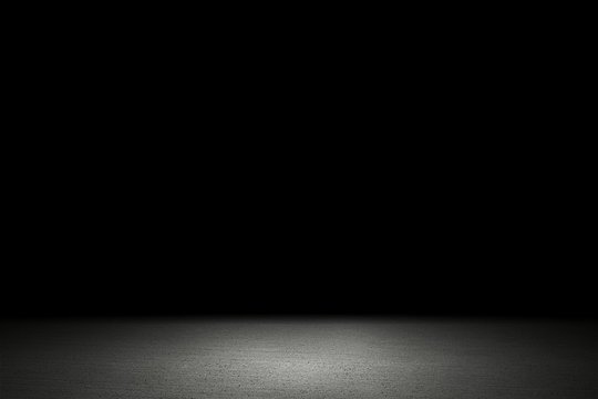 Light shining down on white cement floor in dark room with copy space, abstract background