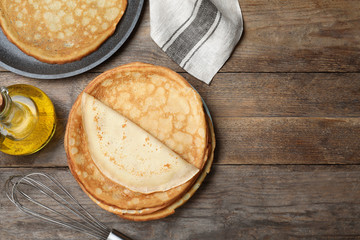 Flat lay composition with thin pancakes on wooden table