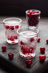 Stacks of vodka and cranberries on a wooden stand and background. Copy of the space. Bar alcoholic beverage tincture.