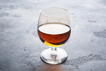 Alcoholic drink in a glass of Cognac brandy. Dark concrete background. Copy space.