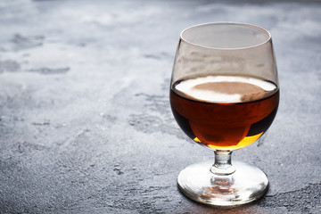 Alcoholic drink in a glass of Cognac brandy. Dark concrete background. Copy space.