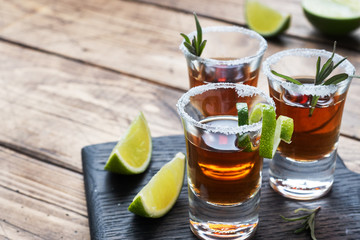 Glass with alcohol, salt and lime on a wooden background. Cognac whiskey tequila. The concept of...