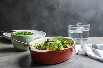 Roasted Brussels sprouts with arugula in baking dish on grey table