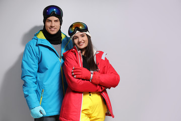 Couple wearing stylish winter sport clothes on light grey background. Space for text