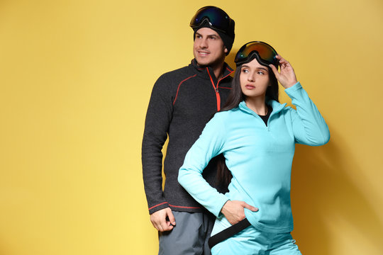 Couple wearing stylish winter sport clothes on yellow background