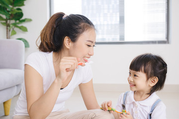 Mother teaching kid daughter teeth brushing at home