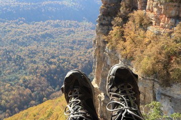 Image of torn trekking boots against the backdrop of mountains.