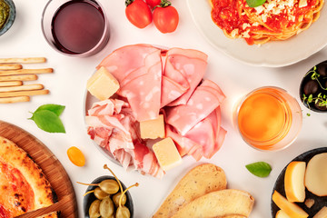 Italian food assortment. Pizza, pasta, cheese, ham, capers, wine, tomatoes, shot from the top on white