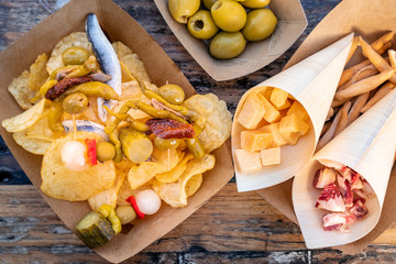 Tapas and pinchos. Cheese, jamon and olives, gildas, fish, potato chips on a wooden table in an...