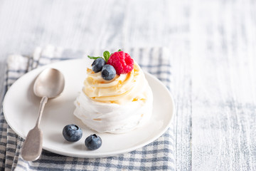 Delicious Pavlova cake with whipped cream and fresh berries on white plate. Scandinavian style. Soft focus