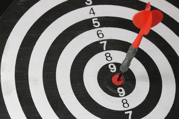 Close up shot of the dart arrow hitting on bull eyes of dartboard to represent that the business reached the target of company with Monochrome tone picture style. target and goal ass concept.